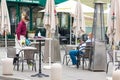 Waiter with a mask disinfects the table of an outdoor bar, cafÃÂ© or restaurant