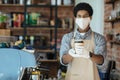 Waiter in medical protective mask serves coffee in restaurant during coronavirus pandemic and new normal Royalty Free Stock Photo