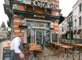 Waiter of old bar coming to entrance of historical Cafe Leffe with outdoor tables