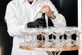 The waiter opens a bottle of champagne, sparkling wine. waiter in black gloves pours champagne into glasses on wooden Royalty Free Stock Photo