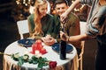 Waiter opens drink of wine. Young lovely couple have romantic dinner indoors together