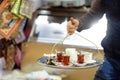 The waiter of outdoors cafe is serving tray with glasses of traditional turkish tea and milk. Istanbul, Turkey. Dishes of turkish