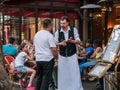 Waiter and patron in intense conversation at sidewalk cafe, Paris