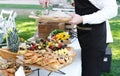 Waiter places food from one plate to another. Catering service. Wedding welcome food. Fruits on skewers and canapes.