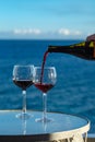 Waiter pouring aperitif red wine in glasses on outdoor tessace witn sea view