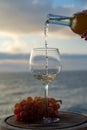 Waiter pouring aperitif white wine in glasses on outdoor tessace witn sea view