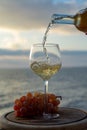 Waiter pouring aperitif white wine in glasses on outdoor tessace witn sea view