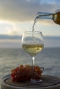 Waiter pouring aperitif white wine in glasses on outdoor tessace witn sea view