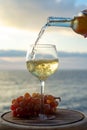 Waiter pouring aperitif white wine in glasses on outdoor tessace witn sea view