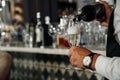 waiter pouring champagne into grocers from a bottle against the background of a bar.