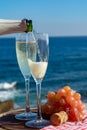 Waiter pouring Champagne, prosecco or cava in two glasses on outside terrace with sea view