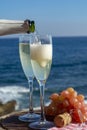 Waiter pouring Champagne, prosecco or cava in two glasses on outside terrace with sea view