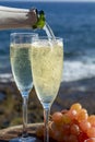 Waiter pouring Champagne, prosecco or cava in two glasses on outside terrace with sea view