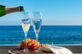 Waiter pouring Champagne, prosecco or cava in two glasses on outside terrace with sea view Royalty Free Stock Photo
