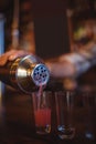 Waiter pouring cocktail drink into shot glasses at counter Royalty Free Stock Photo