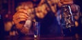 Waiter pouring cocktail drink into shot glasses at counter Royalty Free Stock Photo