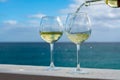 Waiter pouring glass of white wine on outdoor terrace with sea v Royalty Free Stock Photo