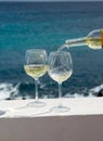 Waiter pouring glass of white wine on outdoor terrace with sea v Royalty Free Stock Photo