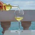 Waiter pouring glass of white wine on outdoor terrace with sea v Royalty Free Stock Photo