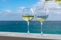 Waiter pouring glass of white wine on outdoor terrace with sea v