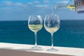 Waiter pouring glass of white wine on outdoor terrace with sea v Royalty Free Stock Photo