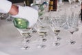 Waiter pouring martini in crystal glasses on table party at wedding reception. Martini row drinks at alcohol bar. Christmas and