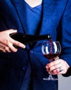 Waiter pouring red wine in a glas. Sommelier man, degustator, winery, male winemaker. Bottle, red wine glass. Pouring