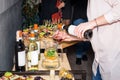 Waiter pouring red wine in a glass at a restaurant table full of appetizers with guests standing near. Royalty Free Stock Photo