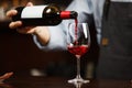 Waiter pouring red wine into wineglass. Sommelier pours alcoholic drink Royalty Free Stock Photo