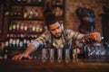 Waiter pouring tequila into shot glasses at counter