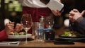 Waiter pouring wine glass at fine restaurant table. Couple enjoy fancy dining. Royalty Free Stock Photo