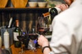 Waiter pouring wine. Skillful sommelier pouring red wine into glass. Woman holding bottle and wineglass standing in Royalty Free Stock Photo