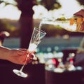 Waiter is pourring sparkling wine into a woman glass at the outdoor party. Celebration concept