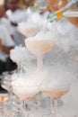The waiter pours champagne into crystal glasses with dry ice and white smoke close up. Sparkling wine pouring in wine Royalty Free Stock Photo
