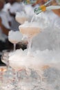 The waiter pours champagne into crystal glasses with dry ice and white smoke close up. Sparkling wine pouring in wine Royalty Free Stock Photo