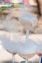 The waiter pours champagne into crystal glasses with dry ice and white smoke close up. Sparkling wine pouring in wine Royalty Free Stock Photo