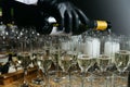 waiter pours champagne into glasses, close-up of the hands