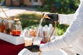 Waiter pours cider into plastic cups from bathroom faucet. Creative welcome drink zone. Bath with ice cubes, fruits Royalty Free Stock Photo