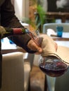 The waiter pours elite red wine into the decanter. Vertical orientation