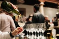 A waiter pours wine from a bottle into a glass