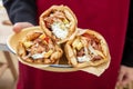 Waiter in red apron presents a plate with three Gyro Pita Shawarma, Souvlaki. Greek, Turkish food Royalty Free Stock Photo