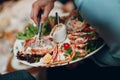 a waiter in a restaurant holds seafood dishes and serves a table catering Concept Healthy food octopus and crabs