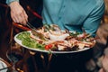 Waiter in a restaurant holds seafood dishes and serves a table catering Concept Healthy food octopus and crabs shellfish