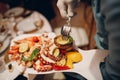 a waiter in a restaurant holds seafood dishes and serves a table catering Concept Healthy food octopus and crabs