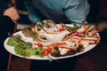 a waiter in a restaurant holds seafood dishes and serves a table catering Concept Healthy food octopus and crabs