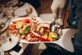 a waiter in a restaurant holds seafood dishes and serves a table catering Concept Healthy food octopus and crabs