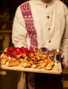 Waiter, servant holding wooden board with variations of chicken barbecue, bbq with grilled bell pepper, tomatoes and sauces.