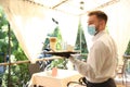 Waiter serving beverages in restaurant. Catering during coronavirus quarantine