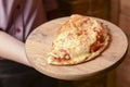 Waiter serving and carrying plate with a tasty big closed italian Calzone pizza. Ham, tomato and cheese. Italian cuisine Royalty Free Stock Photo