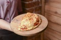 Waiter serving and carrying plate with a tasty big closed italian Calzone pizza. Ham, tomato and cheese. Italian cuisine Royalty Free Stock Photo